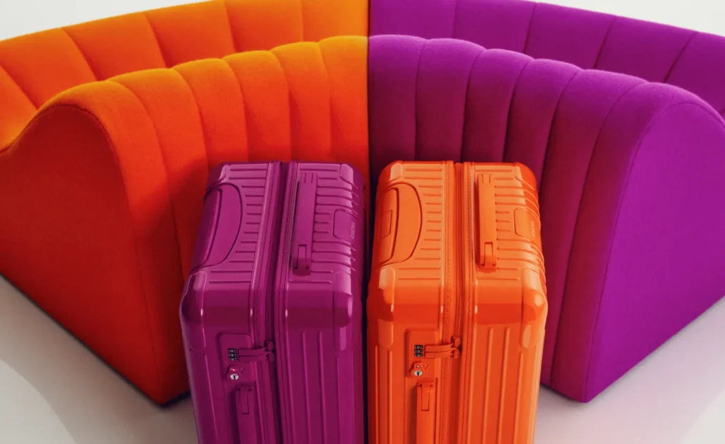 A close-up view from above of RIMOWA suitcases in shades of orange and magenta.
