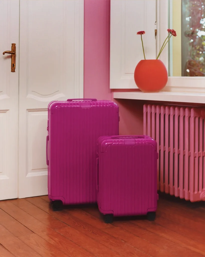 Set of two RIMOWA suitcases in magenta with a pastel interior.