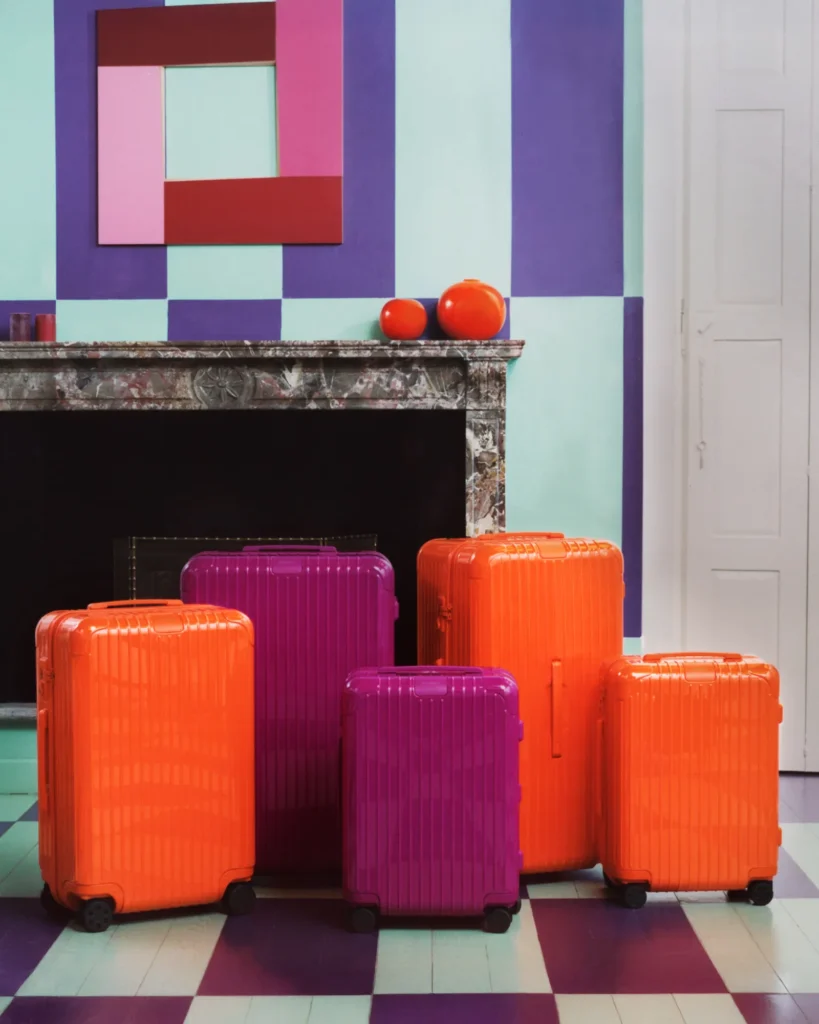 A group of RIMOWA suitcases in the new seasonal colors Orange and Magenta.