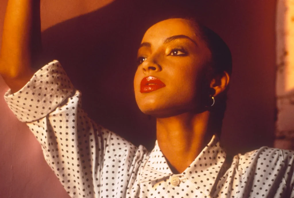 Sade Adu wearing her iconic polka dot shirt and signature red lipstick.