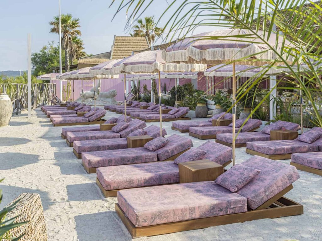 Exclusive Shellona beach club in Saint-Tropez transformed by Dior, featuring pink sunbeds and umbrellas with the traditional Toile de Jouy pattern.