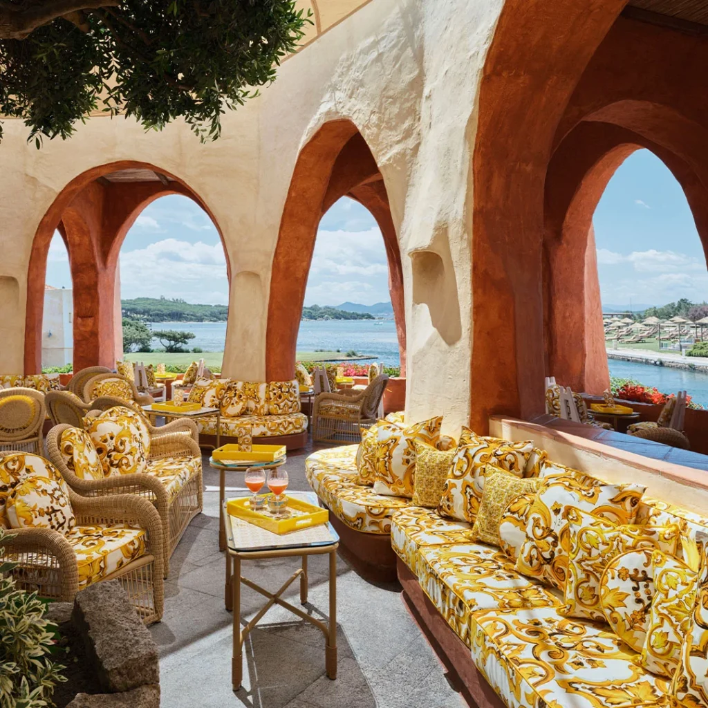 Terrace at Hotel Cala di Volpe in Sardinia featuring yellow sofas adorned with the Mediterranean Maiolica Gialla pattern by Dolce & Gabbana.