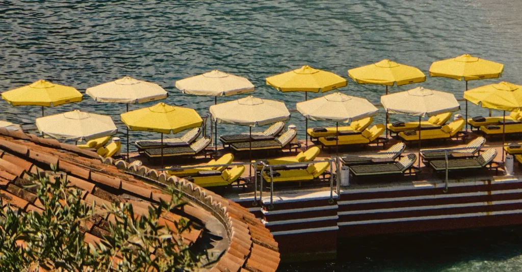 Scenic view of a beach pier in Monaco with yellow and cream umbrellas and sunbeds designed by the French brand Jacquemus by the water.