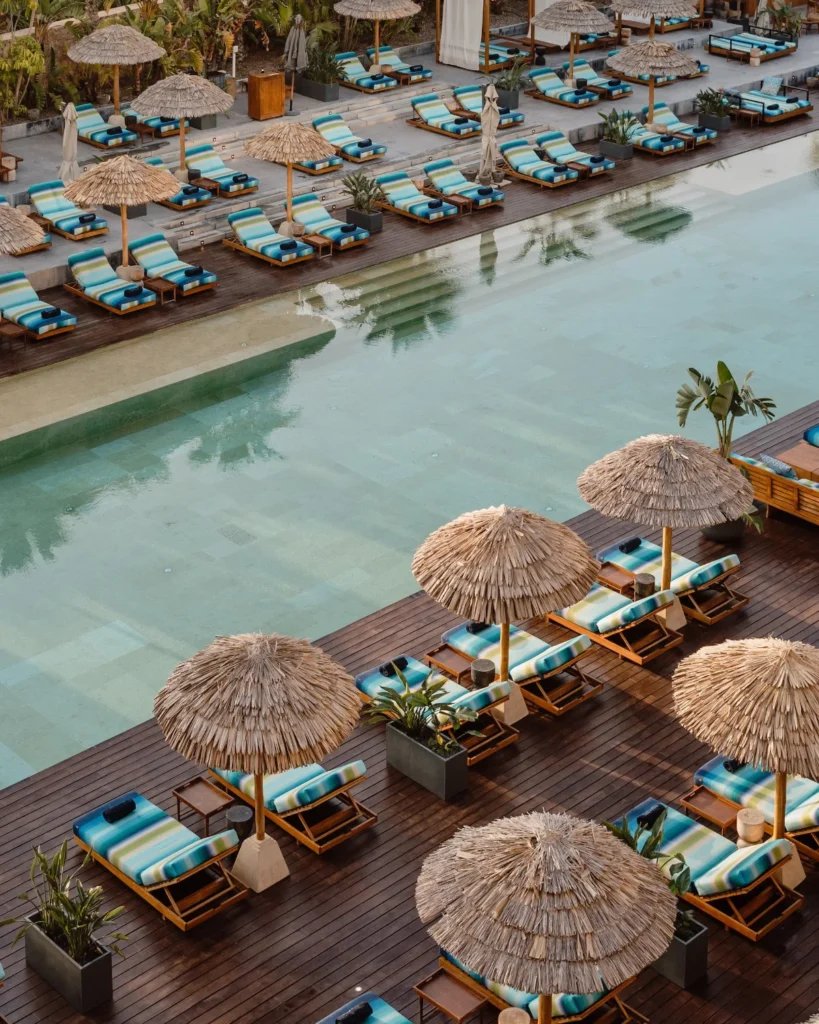 High-angle view of a luxury swimming pool at OKU Ibiza hotel with sunbeds in a light blue and green zigzag pattern by the Italian brand Missoni.
