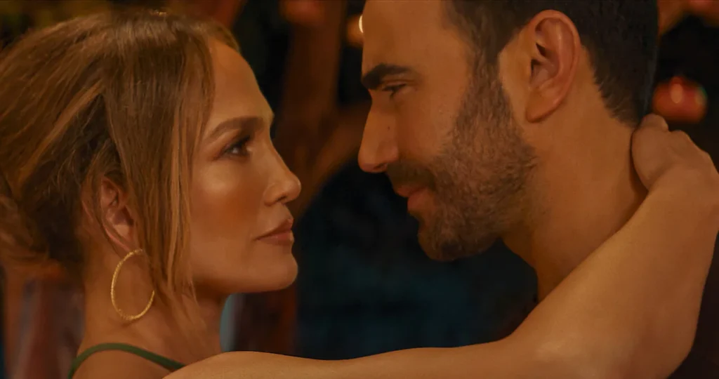 Close-up of Jennifer Lopez and Brett Goldstein looking deeply into each other's eyes in a romantic scene from the movie Office Romance.
