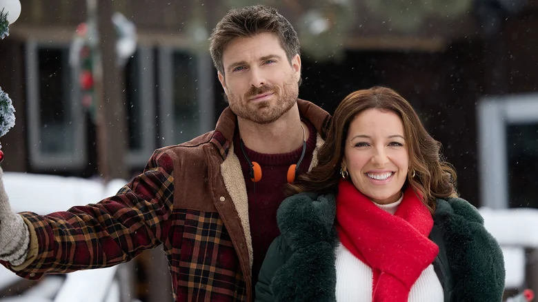 Vanessa Lengies and Marcus Rosner outside a snowy mountain lodge in Hallmark's Snowbound for the Holidays