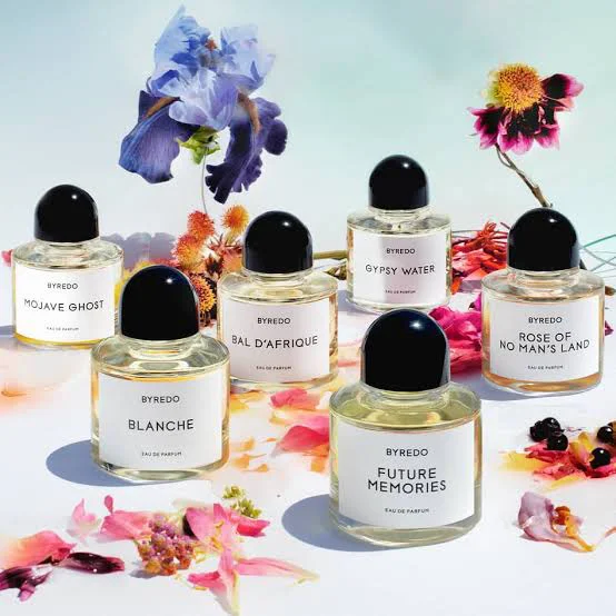 Six Byredo perfume bottles including Blanche, Bal d'Afrique and Mojave Ghost surrounded by colorful flowers