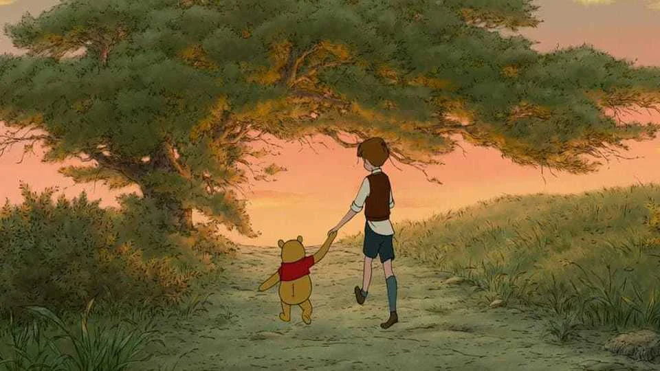 Winnie the Pooh and Christopher Robin hold hands while walking along a woodland path at sunset.