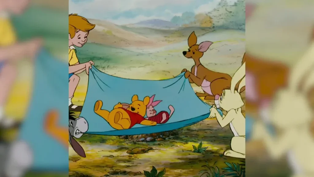 Winnie the Pooh and Piglet rest on a blue blanket held by Christopher Robin and their woodland friends.